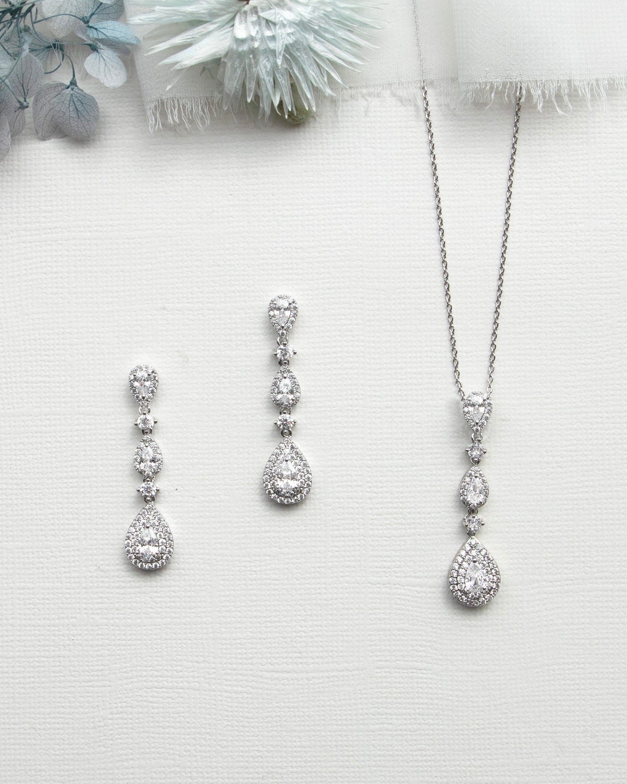 a collection of elegant jewelry pieces, including a necklace, earrings, and a pendant, all featuring a sparkling diamond design.