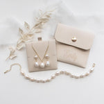 A beige jewelry box with pearls, a necklace, and a bracelet are arranged on a white background.