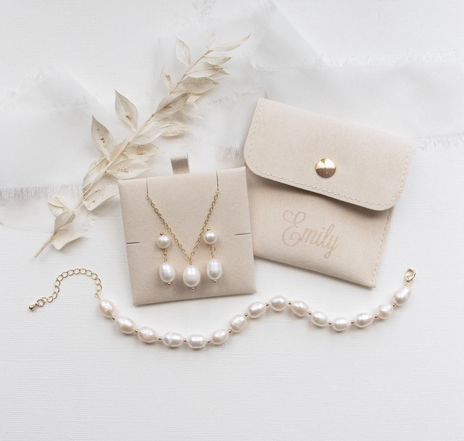 A beige jewelry box with pearls, a necklace, and a bracelet are arranged on a white background.
