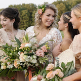 A group of women, presumably bridesmaids, standing together and holding bouquets of flowers.