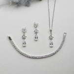 a necklace, bracelet, and earring set on a white surface