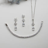a necklace, bracelet, and earring set on a white surface