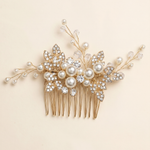 A decorative gold hairbrush adorned with pearls and crystal embellishments.