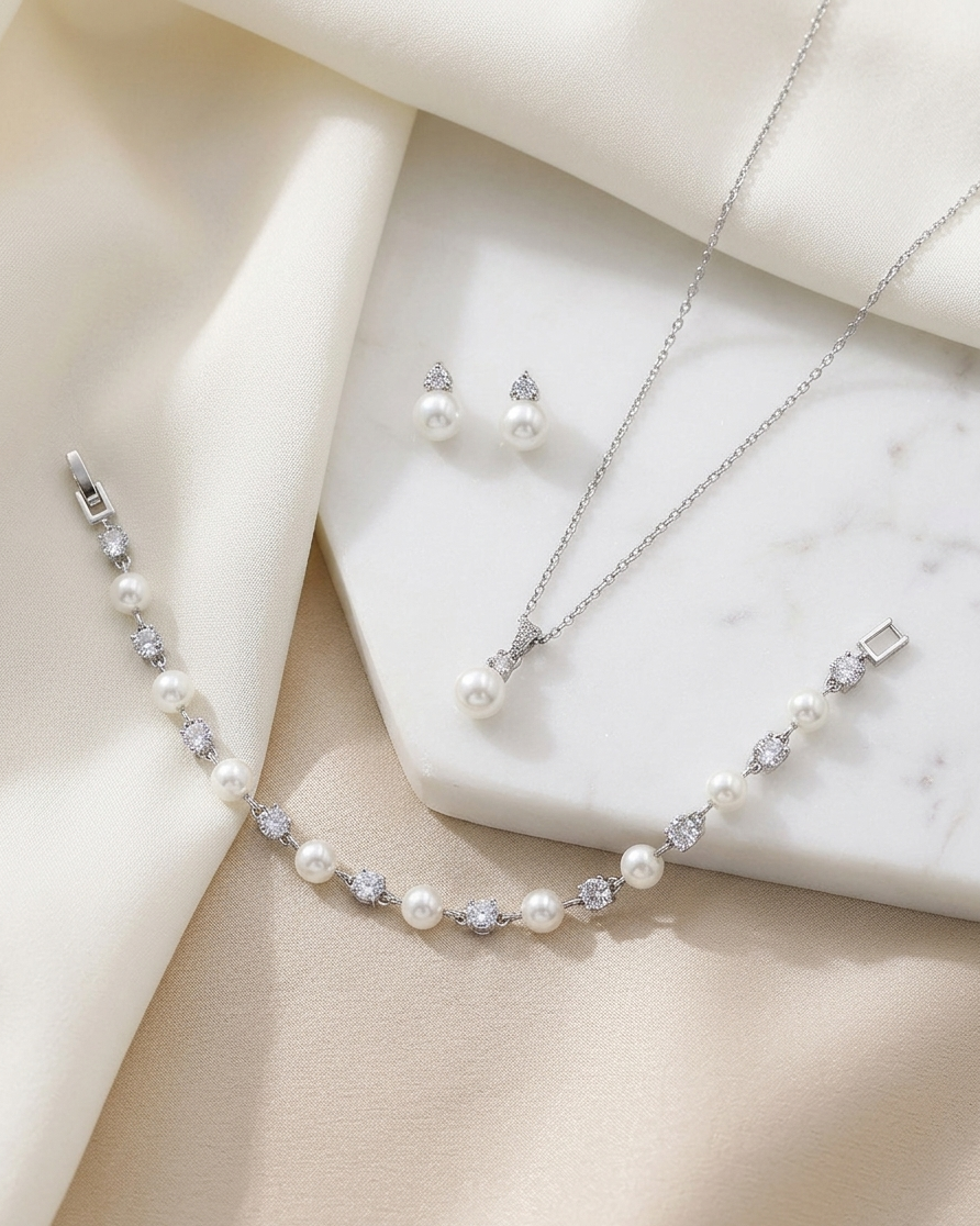 A delicate necklace, bracelet, and earrings are arranged on a white marble surface, creating an elegant and sophisticated display.