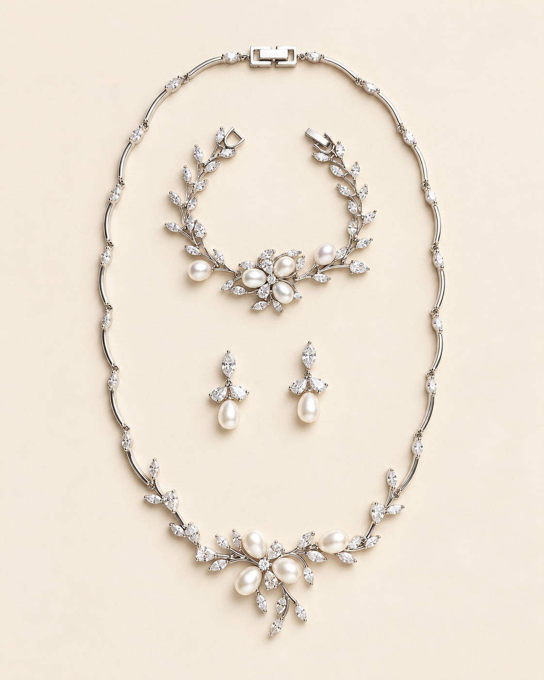 Dahlia silver pearl and crystal three-piece jewelry set with necklace, earring pair and bracelet on a cream background.