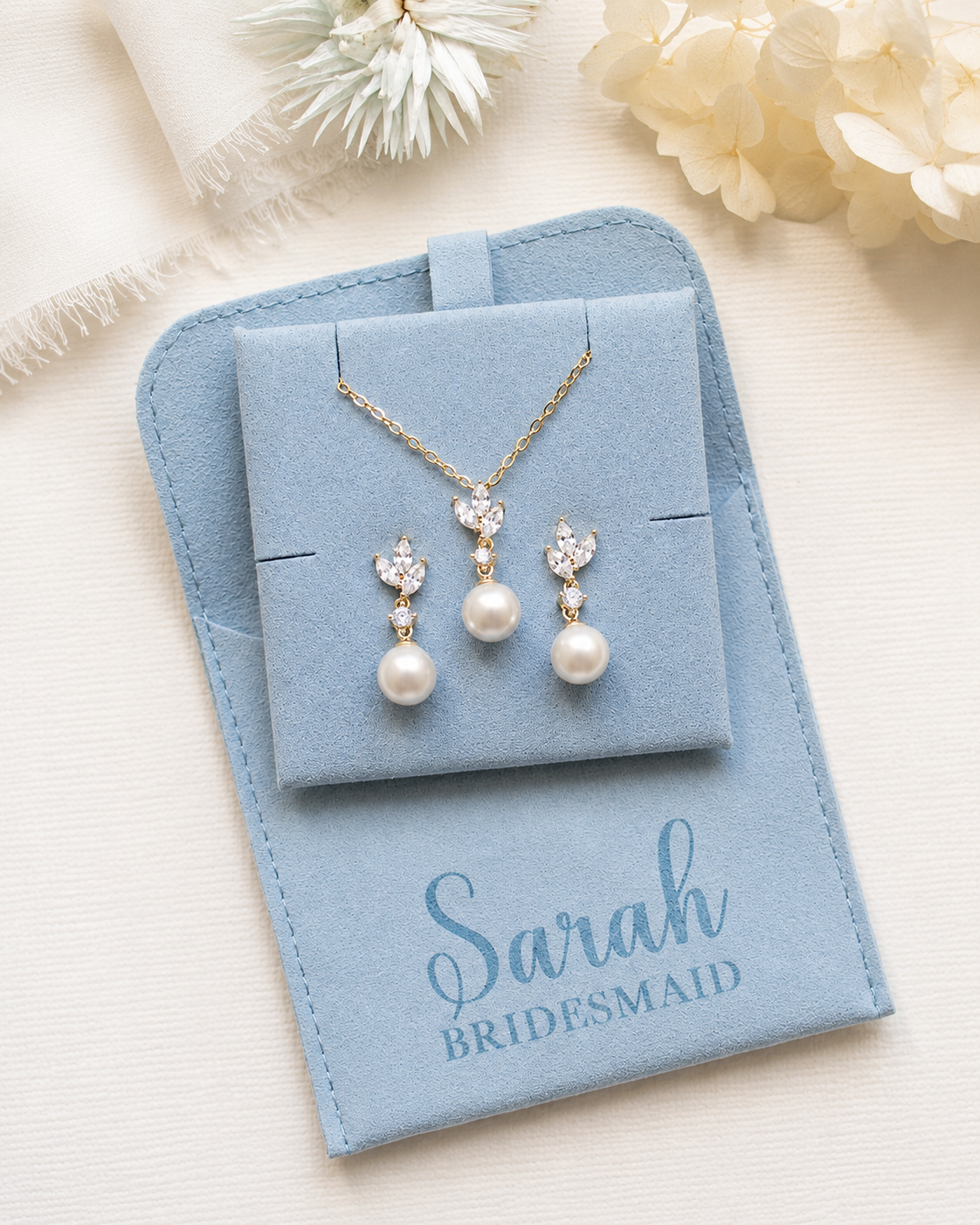 A light blue jewelry box containing a necklace and earrings, with a personalized message that says "Sarah Bridesmaid" printed on the front.