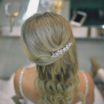 a woman with her hair styled in an elegant updo, wearing a decorative hair accessory.