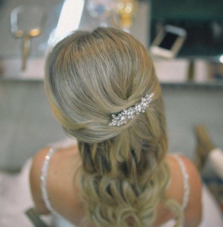 a woman with her hair styled in an elegant updo, wearing a decorative hair accessory.
