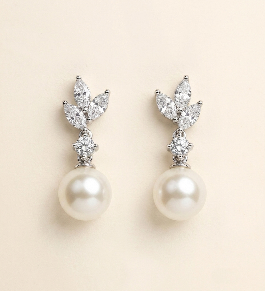 A pair of elegant earrings with a pearl at the bottom and a cluster of diamonds on top.