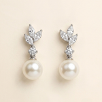 A pair of elegant earrings with a pearl at the bottom and a cluster of diamonds on top.