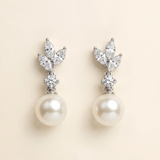 A pair of elegant earrings with a pearl at the bottom and a cluster of diamonds on top.