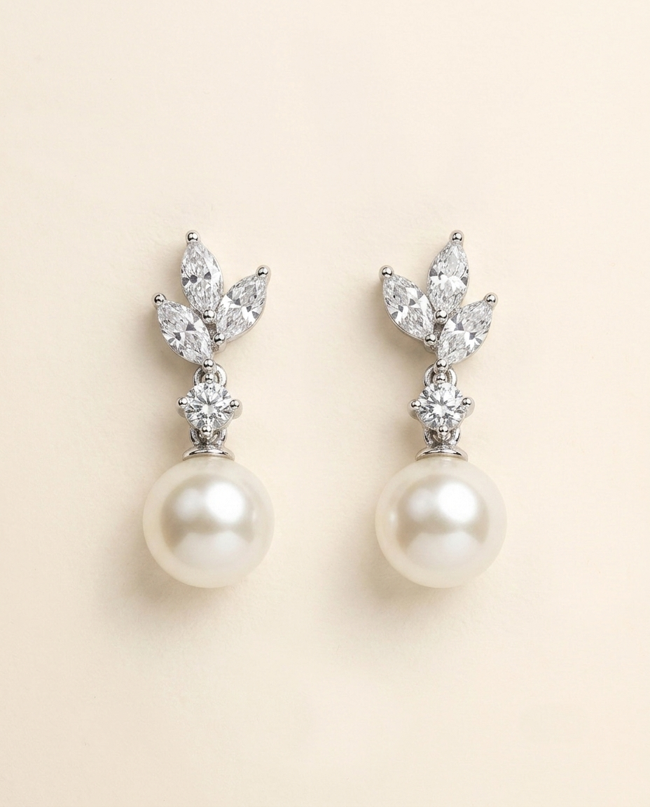 A pair of elegant earrings with a pearl at the bottom and a cluster of diamonds on top.