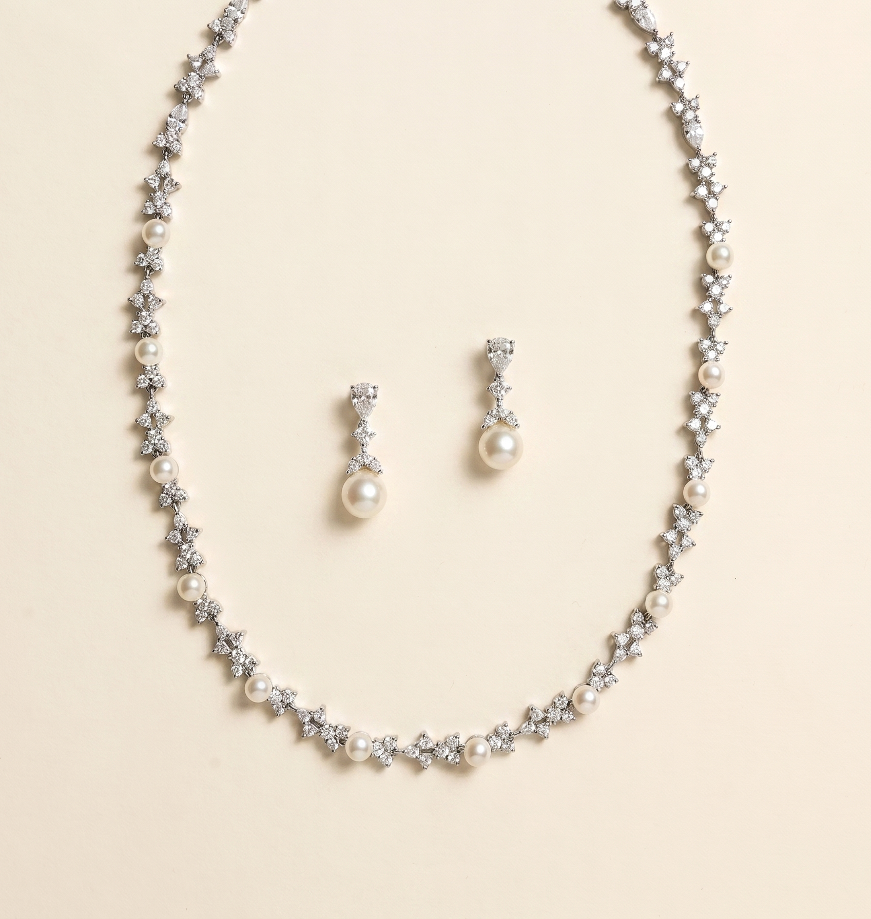 A necklace and earrings set made of silver and white pearls and diamonds.