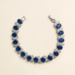 A bracelet with a row of blue sapphires and diamonds set in silver.