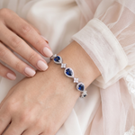 A close-up image of a person's hand wearing a bracelet with blue gemstones.