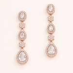 A pair of elegant gold earrings with clear gemstones, featuring a row of three stones on each earring.
