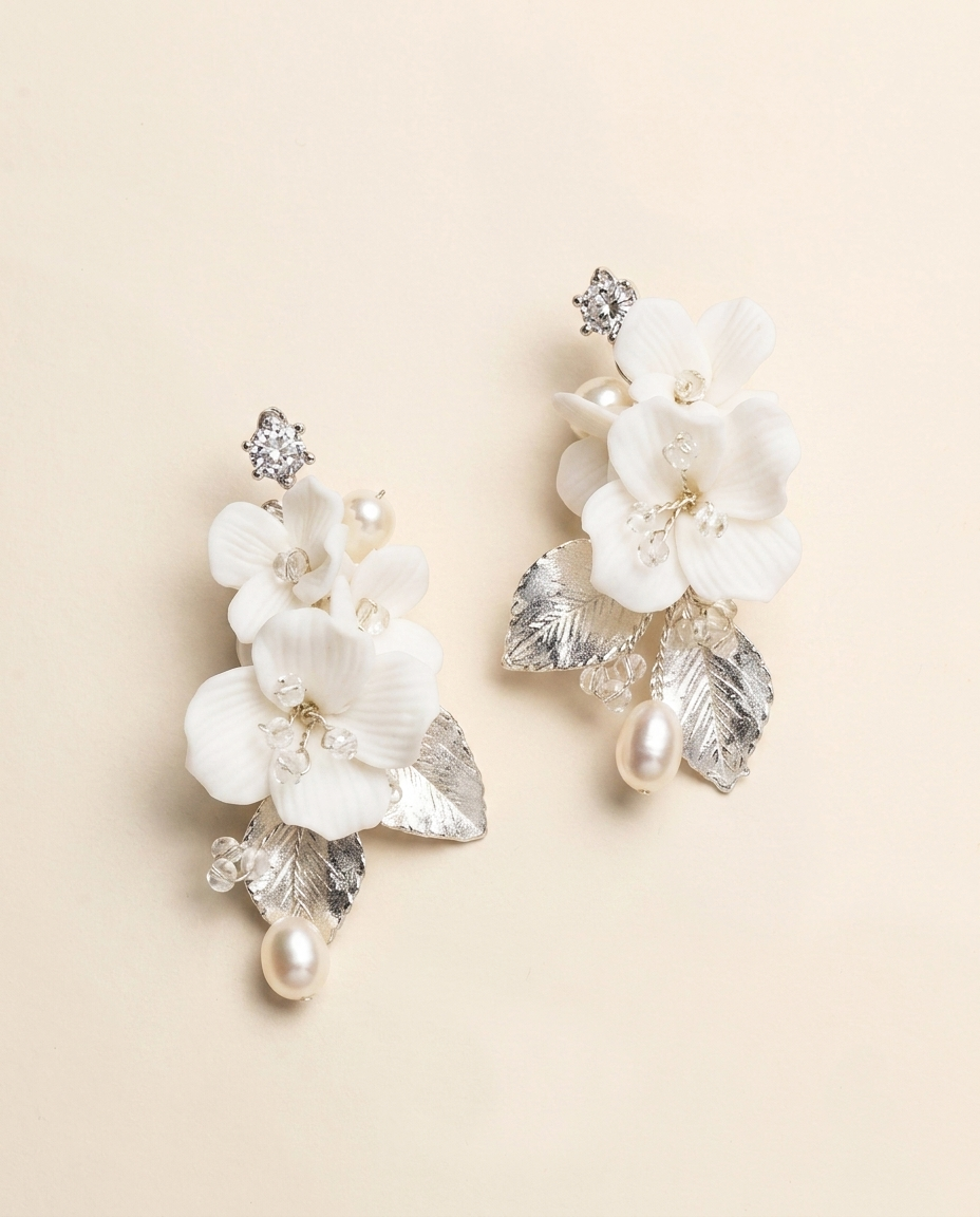 A pair of elegant white floral earrings with silver leaves and pearls.