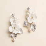 A pair of elegant white floral earrings with silver leaves and pearls.