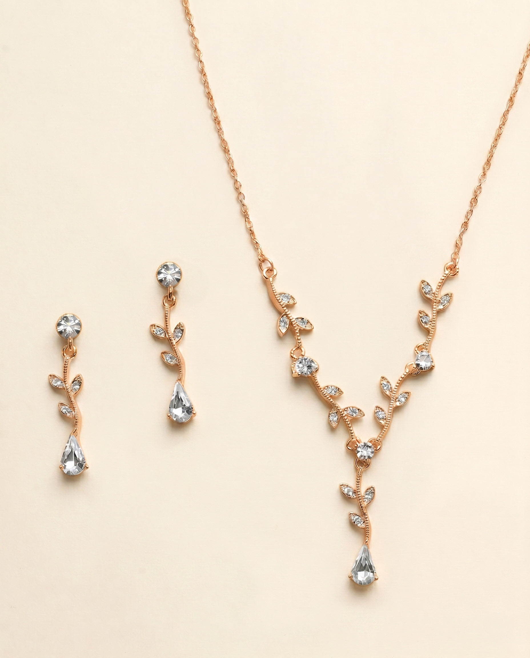 A delicate gold necklace and earrings set adorned with small, clear gemstones.