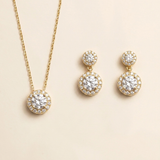 A gold necklace with a pendant and a pair of earrings with a similar design.