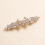 A decorative hair clip with a floral design and numerous small, clear gemstones.