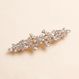 A decorative hair clip with a floral design and numerous small, clear gemstones.