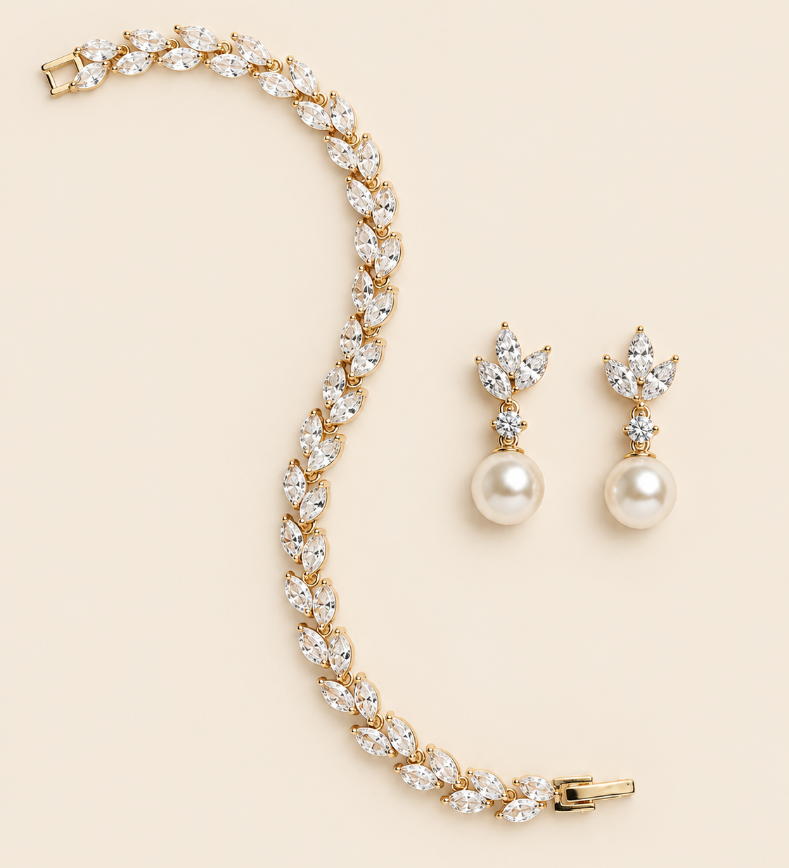 Eve gold pearl-drop earring pair and marquise crystal bracelet on a cream background.