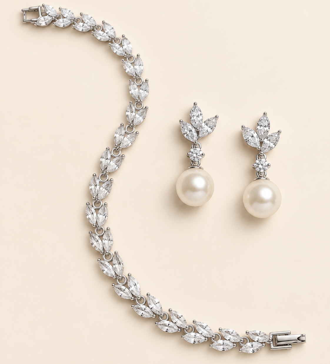 Eve silver pearl-drop earring pair and marquise crystal bracelet on a cream background.