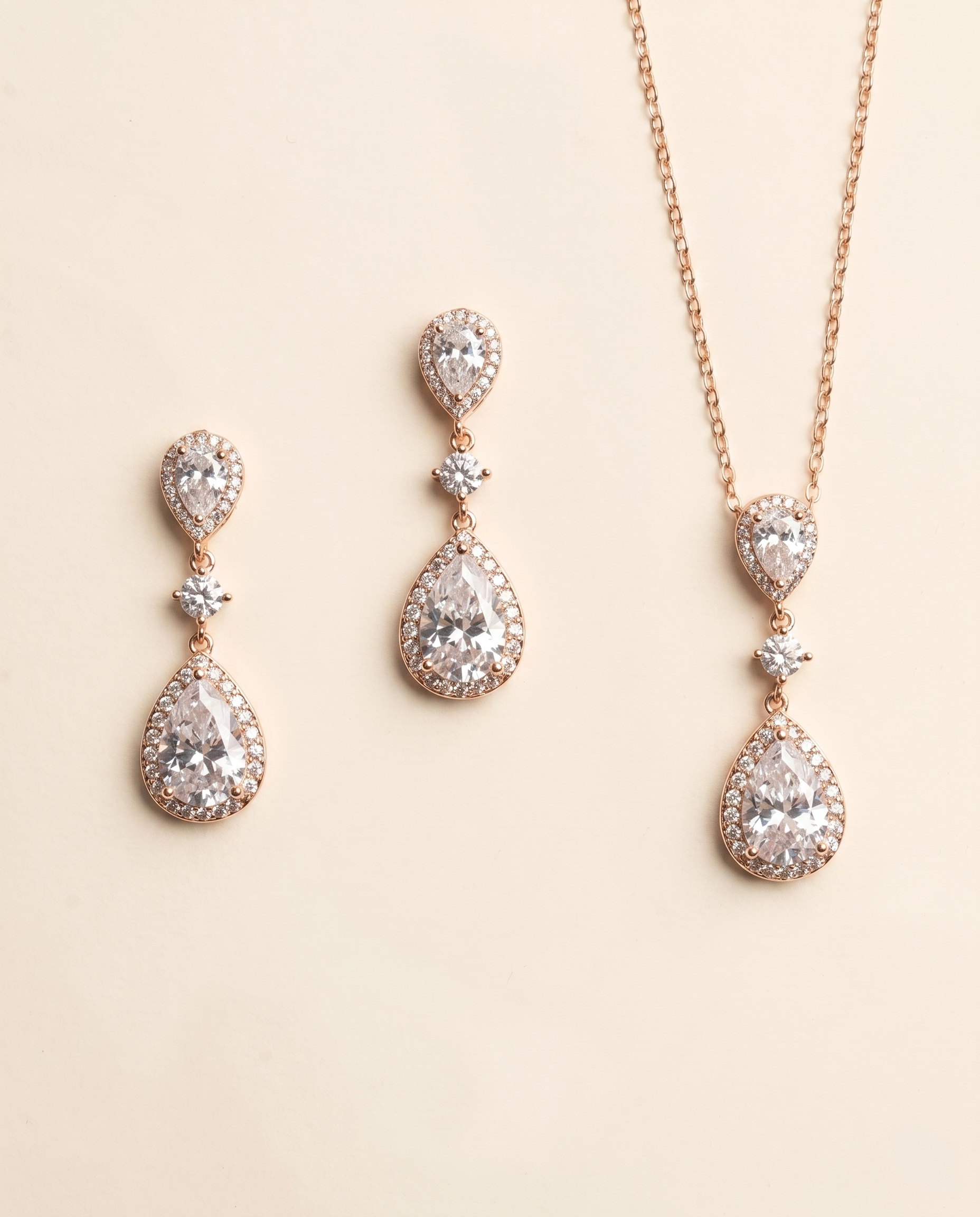 a set of elegant jewelry pieces, including earrings and a necklace, featuring a combination of pear-shaped and teardrop-shaped stones, as well as a chain.