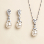 A necklace and earrings set featuring a pendant and earrings with pearls and diamonds.