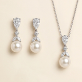 A necklace and earrings set featuring a pendant and earrings with pearls and diamonds.