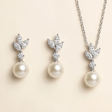 A necklace and earrings set featuring a pair of pearl drop earrings and a pendant with a leaf design.