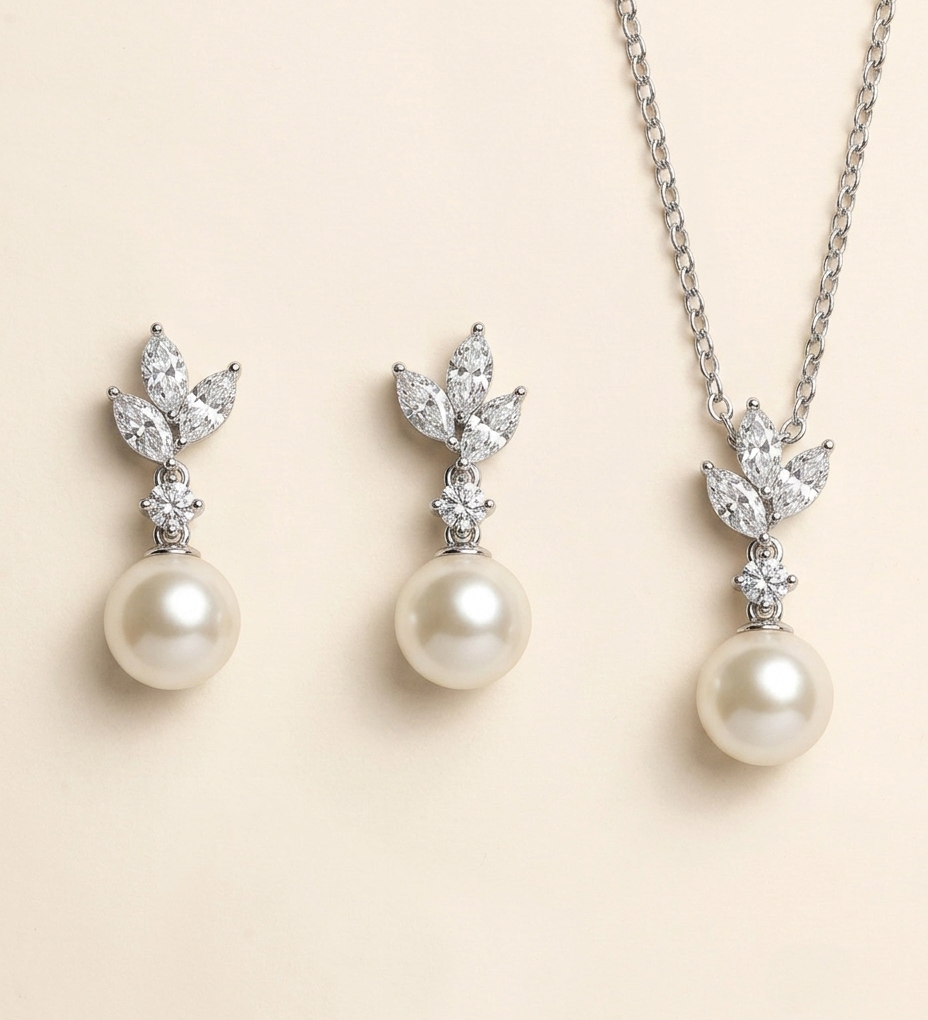 A necklace and earrings set featuring a pair of pearl drop earrings and a pendant with a leaf design.