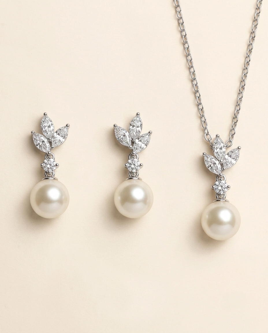 A necklace and earrings set featuring a pair of pearl drop earrings and a pendant with a leaf design.