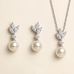 A necklace and earrings set featuring a pair of pearl drop earrings and a pendant with a leaf design.