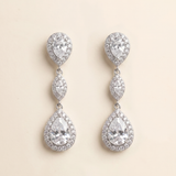 A pair of elegant earrings with a large central crystal surrounded by smaller pear-shaped and teardrop-shaped stones, all set in a silver-toned metal.