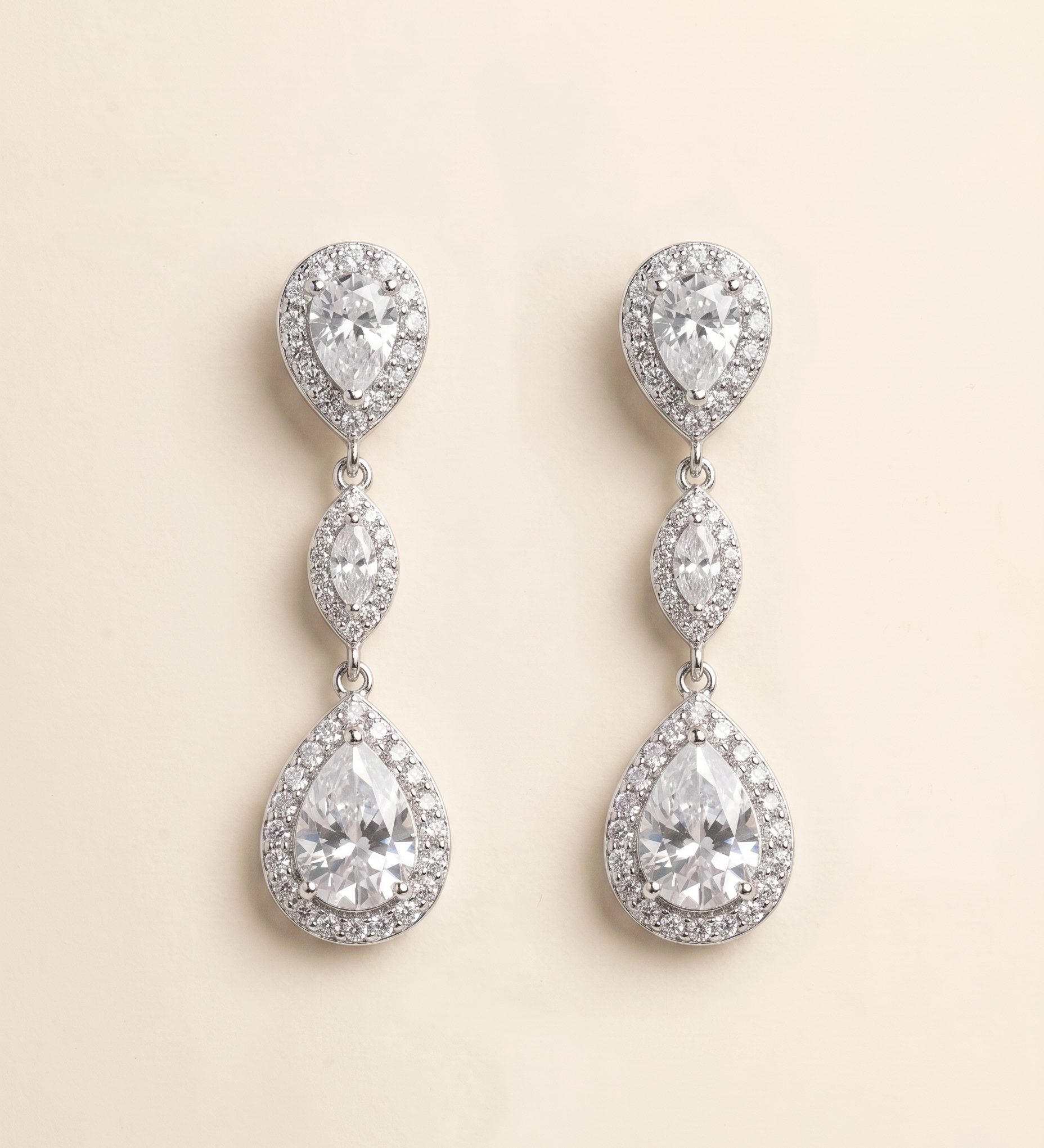 A pair of elegant earrings with a large central crystal surrounded by smaller pear-shaped and teardrop-shaped stones, all set in a silver-toned metal.