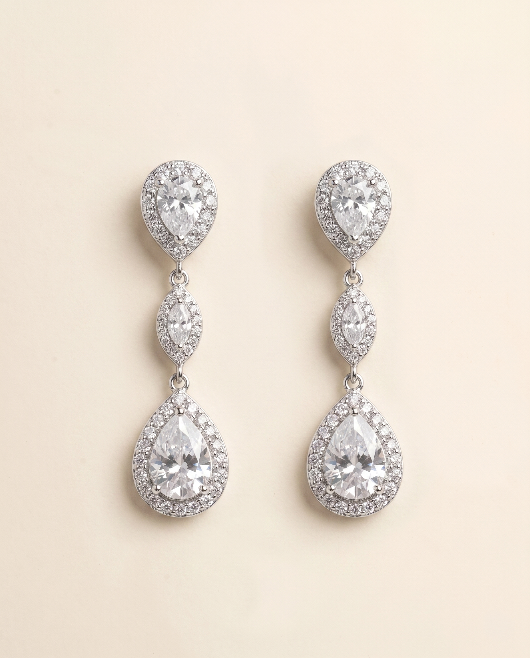 A pair of elegant earrings with a large central crystal surrounded by smaller pear-shaped and teardrop-shaped stones, all set in a silver-toned metal.