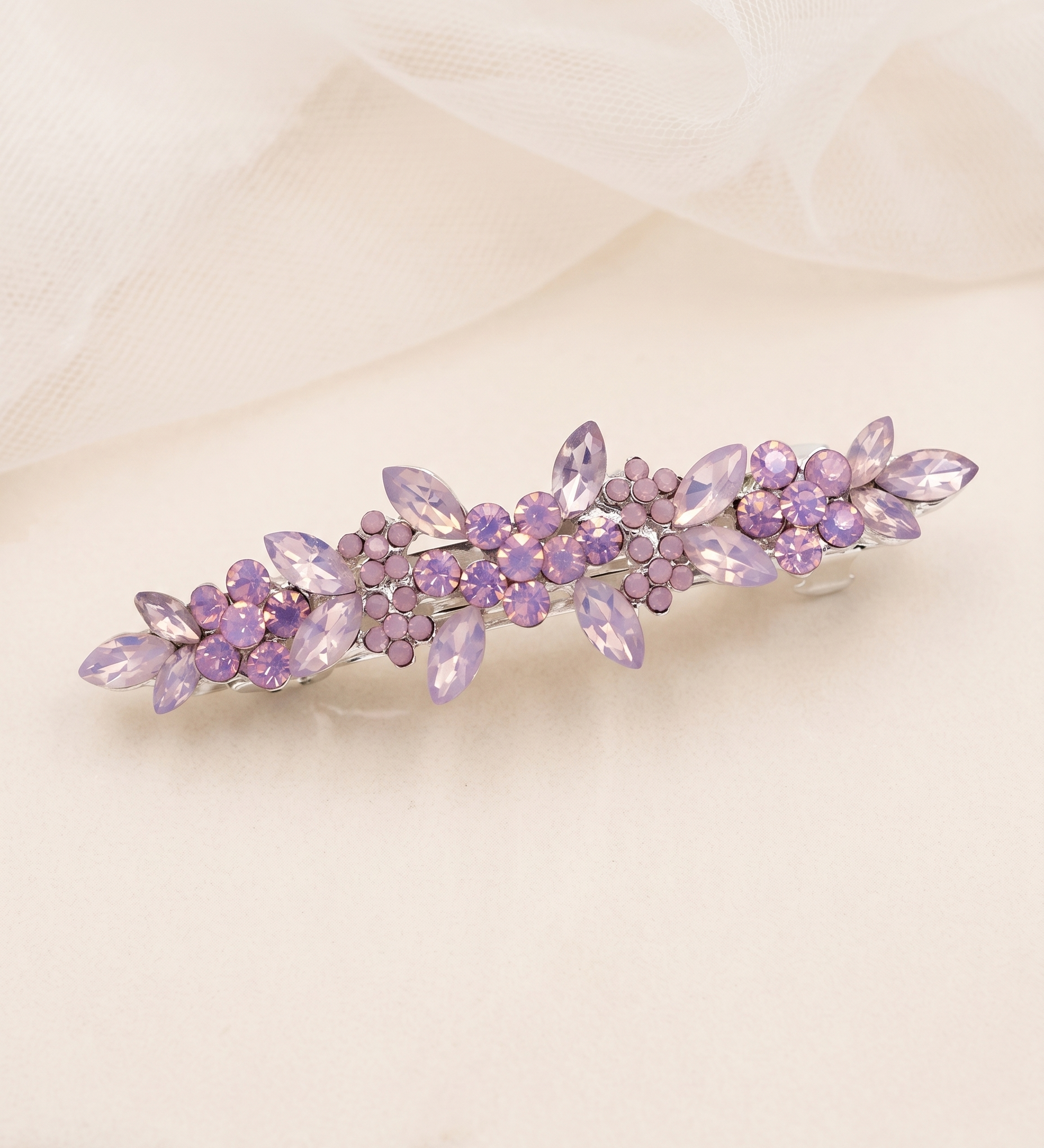 A decorative hair clip with purple flowers and gemstones is displayed on a light-colored surface.