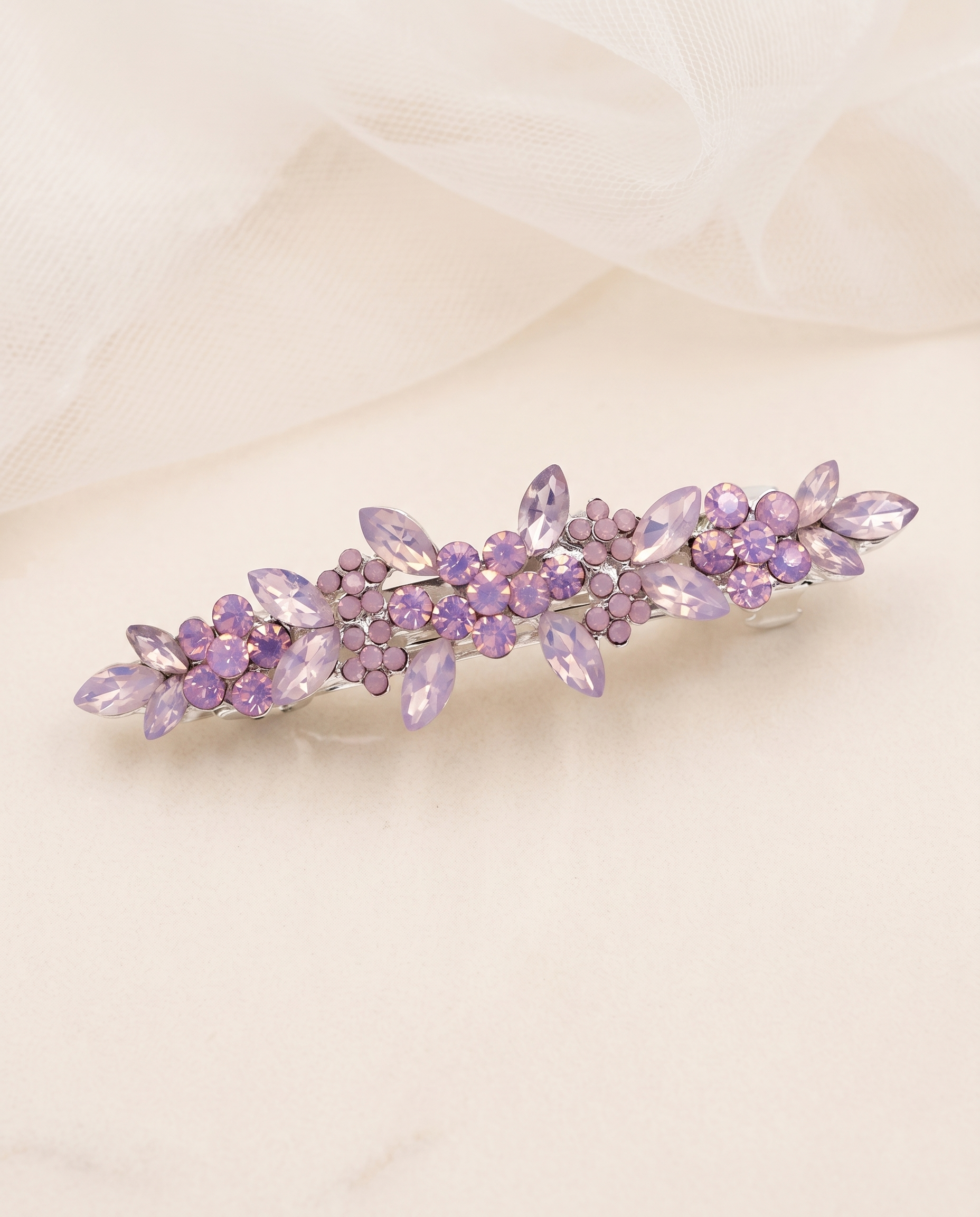 A decorative hair clip with purple flowers and gemstones is displayed on a light-colored surface.
