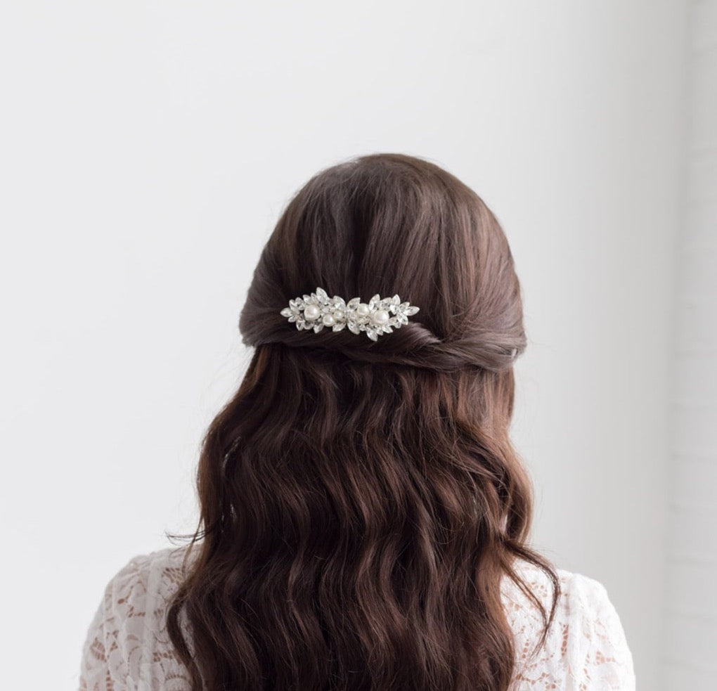 the back view of a woman with long, dark hair styled in a twisted updo, wearing a white lace top.