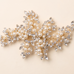 A decorative piece of jewelry with a combination of pearls, crystals, and leaves.