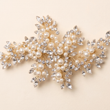 A decorative piece of jewelry with a combination of pearls, crystals, and leaves.