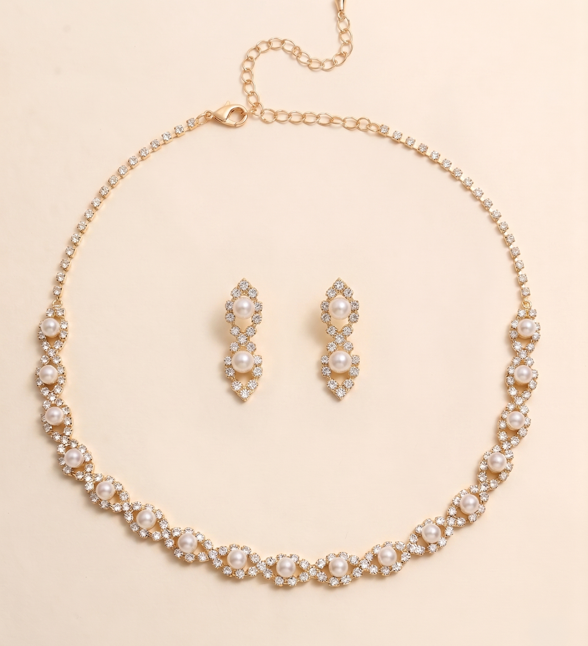 A gold necklace and earrings set are displayed on a light beige background.