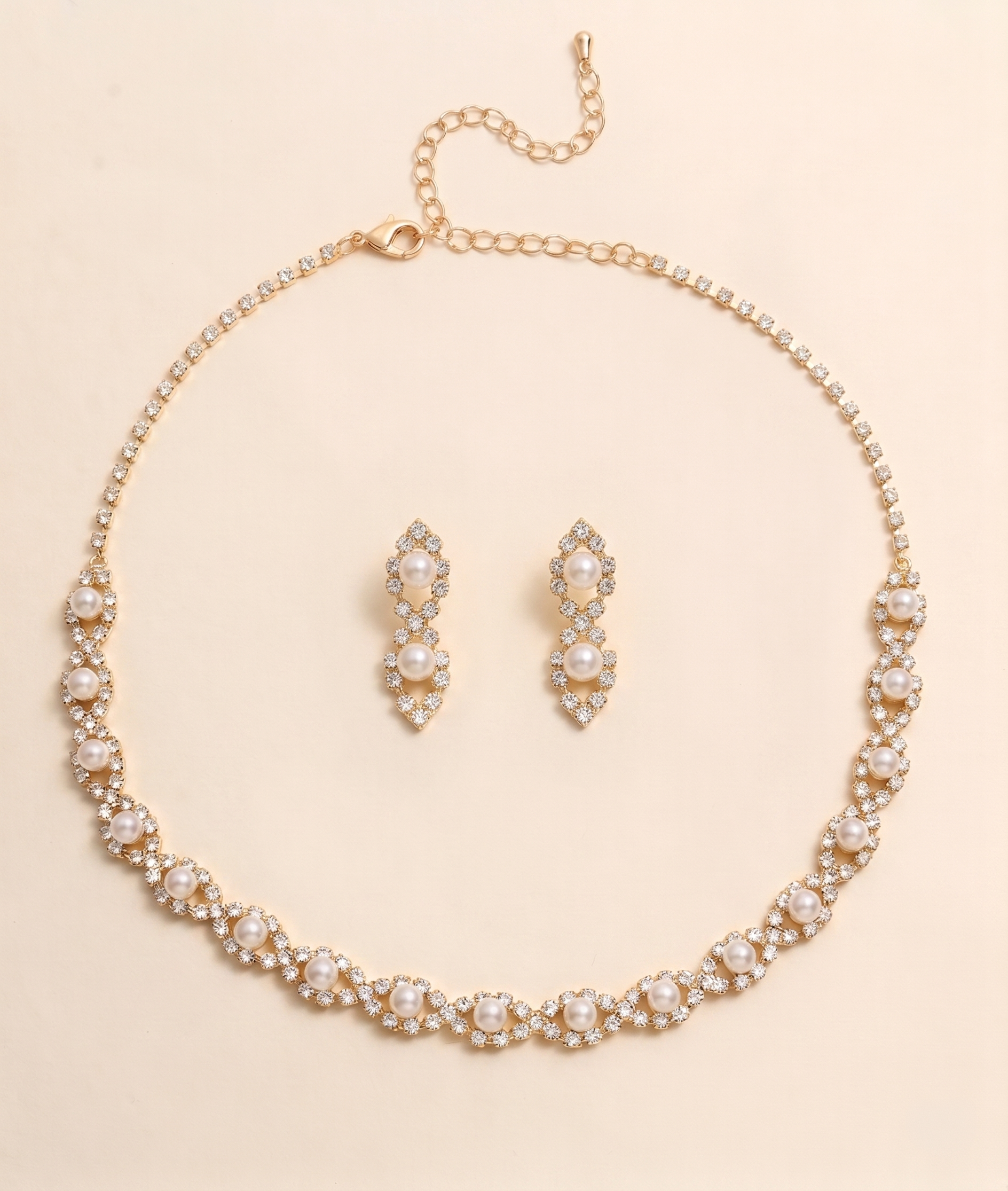 A gold necklace and earrings set are displayed on a light beige background.