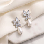 Gabriella silver-finish bridal earrings with marquise floral clusters and white pear-shaped drops on ivory fabric