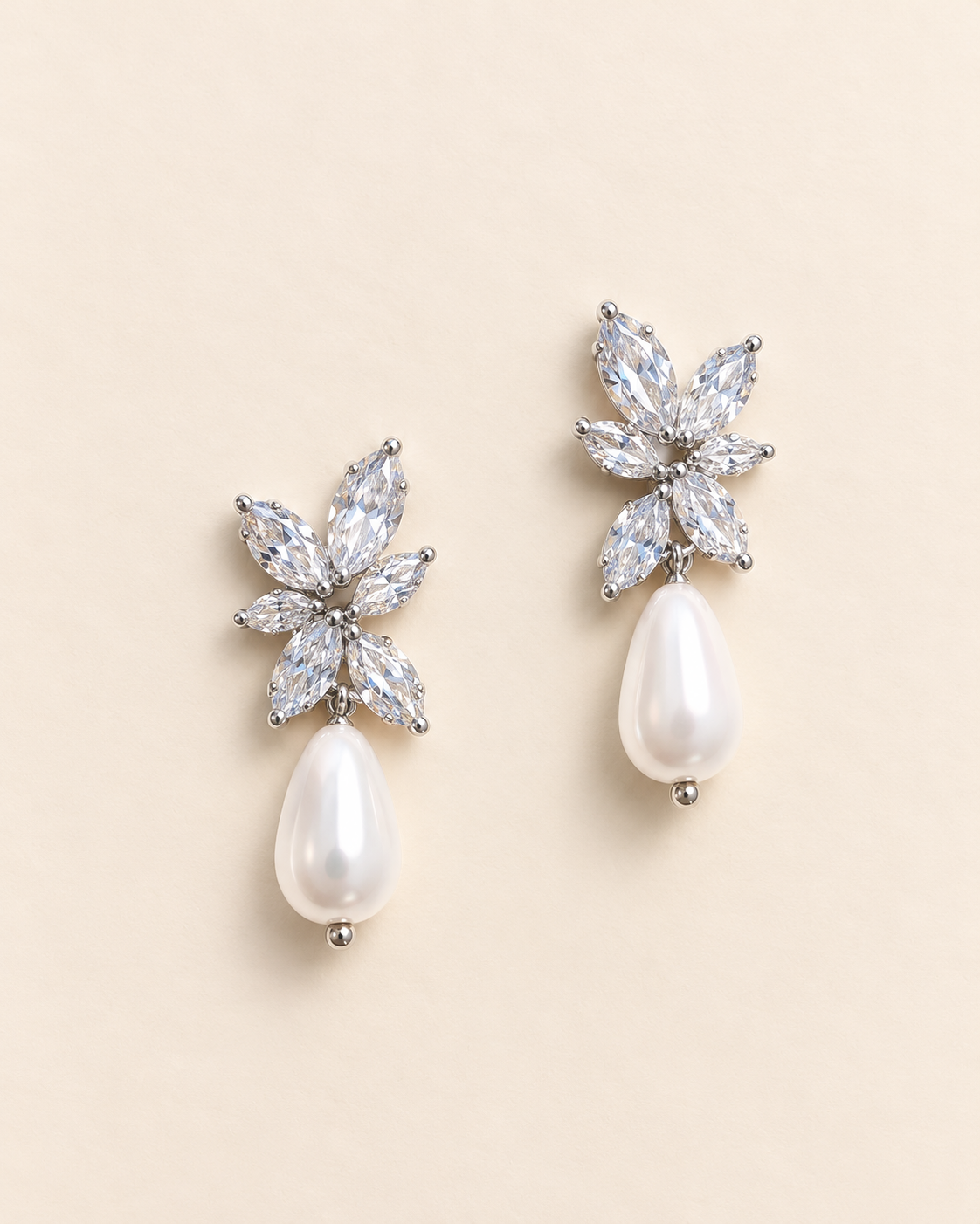 Pair of Gabriella silver-finish earrings with clear marquise floral clusters and white teardrop accents on an ivory background