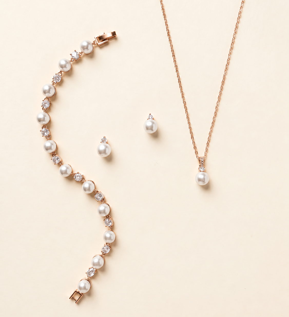 Jennifer rose gold pearl and crystal earrings, necklace and bracelet three-piece jewelry set on cream background