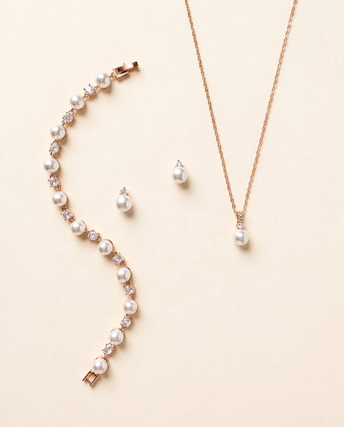 Jennifer rose gold pearl and crystal earrings, necklace and bracelet three-piece jewelry set on cream background