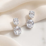 Josephine silver-finish bridal earrings with two clear cushion-shaped accents on ivory fabric